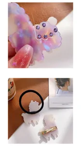 Detail van alpaca haarspeld van acetaat met paarse strassteentjes en bijpassend haarelastiek.