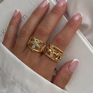Detailed view of 18k gold plated stainless steel starfish and palm tree rings on hand.