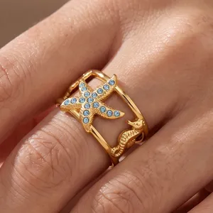Detail view of gold plated stainless steel starfish and seahorse ring with blue crystals
