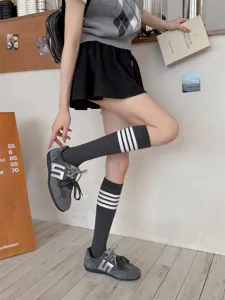 Grey knee-high socks with white stripes, paired with sneakers in a chic daily outfit detail.