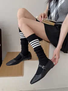 Japanese style black knee high socks with white stripes paired with Mary Jane shoes for women.
