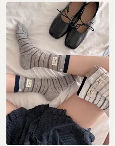 Chaussettes mi-mollet rayees de style coreen avec bouton et etiquette, vetement doux et casual.