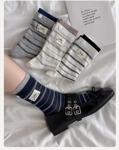 Vue rapprochée de chaussettes mi-mollet rayées avec étiquettes en tissu décoratives et boutons élégants.