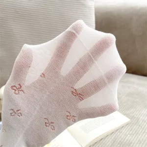 Close-up detail of sheer white women's socks with cute red bow print and elastic stretch.