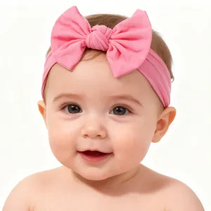 Nahaufnahme eines glücklichen lächelnden Babys mit einem weichen rosa Nylon-Stirnband mit Schleife