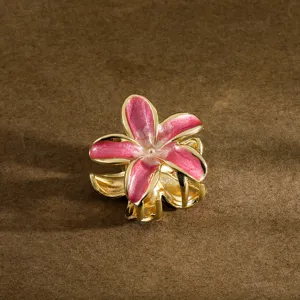 Macro detail of a pink frangipani flower hair claw clip with gold metal finish