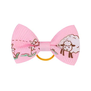 Primo piano di elastico per capelli con fiocco in gros-grain rosa e stampa pecorella d'oro.