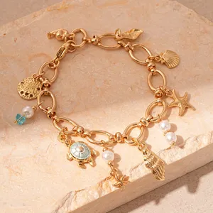 Close-up detail of a gold-tone ocean-themed charm bracelet with pearls and starfish charms