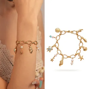 Gold ocean-themed bracelet featuring shell charms, starfish and pearl tassels on wrist