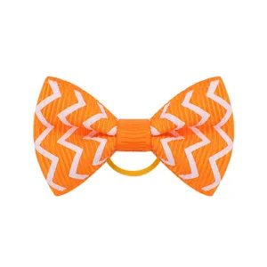 Dettaglio di fiocco per capelli arancione con motivo a zigzag bianco ed elastico