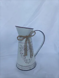 Λεπτομέρεια vintage λευκού σιδερένιου βάζου κανάτας με σχέδιο καρδιάς και φιόγκο από γιούτα