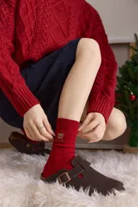 Detailaufnahme roter Baumwoll-Socken mit süßer Bärenstickerei und gemütlicher Textur.