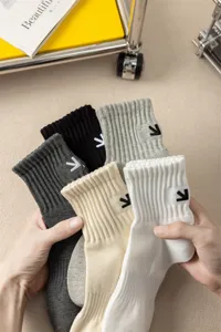 Dettaglio primo piano di calze uomo con freccia ricamata cotone morbido a coste multicolore.