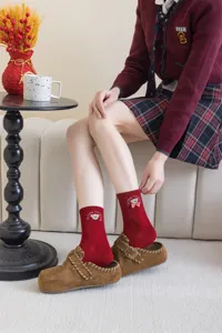 Detailed shot of cute red mid-tube socks featuring charming bear embroidery and a bow knot accessory.