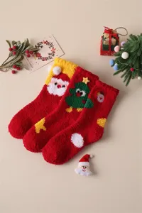 Cozy coral fleece Christmas socks detail showing cute Santa Claus and tree patterns on warm background.
