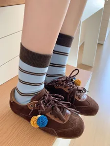 Stylish women's mid-calf striped socks paired with retro brown suede casual sneakers.