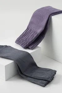 Detailed shot of ribbed long socks in purple and grey colors displayed neatly on white blocks.