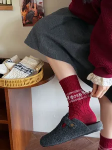 Detailed view of cozy red wool Christmas socks with festive snowflake and elk knit patterns.