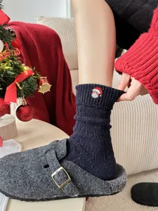 Close-up detail of cozy navy blue winter wool socks featuring cute Santa embroidery.