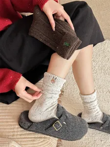 Thick wool Christmas socks detail featuring cute reindeer embroidery, cozy speckled yarn.