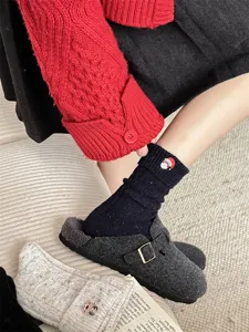Detailed shot of thick winter wool Christmas socks with cute Santa embroidery and cozy turned cuff.
