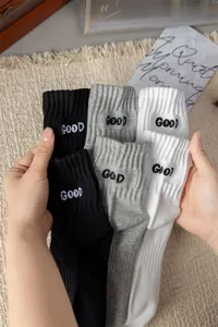 Detailed view of men's crew socks featuring embroidered letter details and soft cotton fabric.