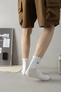 Men's mid-tube cotton socks with blue letter embroidery, street style detail view.