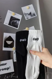Close-up detail of men's mid-tube combed cotton socks with embroidered letter designs.