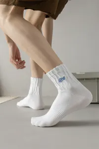 Men's white cotton crew socks featuring stylish blue letter embroidery for casual streetwear.