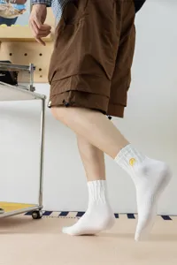 Men's white cotton mid-calf socks featuring trendy yellow lightning embroidery, detail shot.