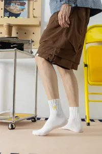 Detail view of men's white cotton crew socks featuring yellow lightning embroidery design.