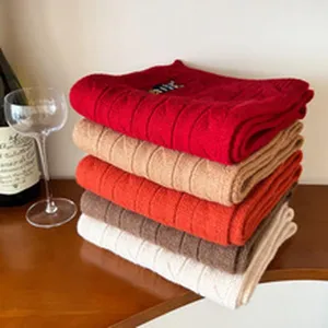 Folded knit sweaters stack in multiple colors with cozy vintage style and warm lifestyle background.