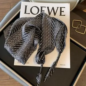 Vue détaillée d'un foulard triangulaire à motif noir et blanc avec de beaux glands.