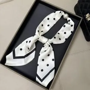 Vue détaillée du foulard en soie à pois blancs, bordure noire élégante et perle.