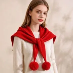 Red knitted triangular scarf detail showing soft wool texture and cute pom poms for women.