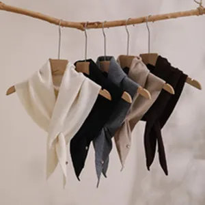 Detailed view of cozy knitted triangular scarves in multiple chic colors hanging neatly.