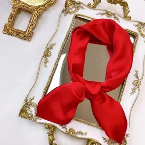 Silk small square scarf detail view, elegant red satin design for stylish neck wear.