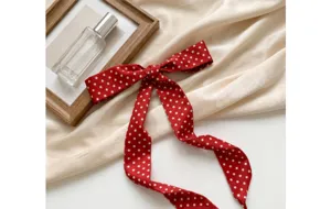 Detail view of a red polka dot silk ribbon scarf, elegant hair band and neck accessory.