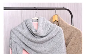 Dettaglio di scialle in lana lavorata a maglia grigia con morbida consistenza invernale.