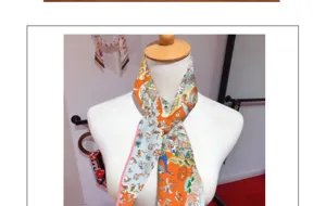 Detail shot of a luxurious twill silk narrow scarf showcasing vibrant multicolored artistic prints.