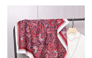 Λεπτομερής όψη του vintage κόκκινου και μπλε κασμίρ μαντηλιού σε κρεμάστρα ρούχων.