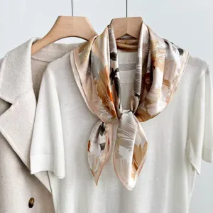 Elegant silk square scarf with abstract floral print, styled on a white knit top detail.