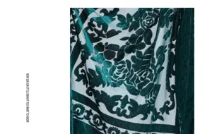 Detailed view of a luxurious green velvet shawl fabric with vintage floral relief design.