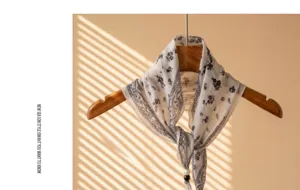 Detail view of a vintage bohemian floral print bandana scarf hanging on a wooden hanger.