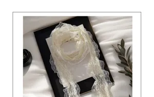 Close-up of white lace ribbon scarf, delicate floral pleats for elegant styling detail.