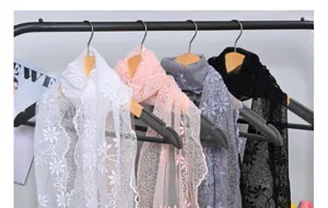 Detailed view of delicate floral lace scarves hanging on hangers, showcasing soft embroidery and texture.