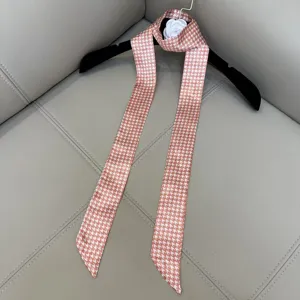 Detailed view of the pink and white houndstooth slim silk twilly scarf with elegant aesthetic.
