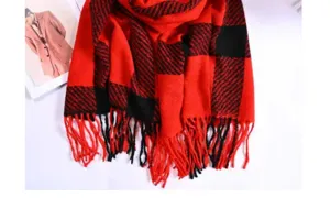 Red and black plaid winter scarf detailed view with fringe texture and soft warm fabric.