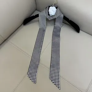 Black and white houndstooth skinny scarf with chic floral accessory for women fashion.