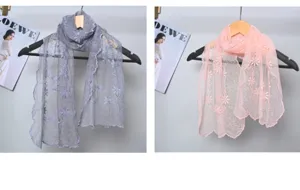 Detail view of floral embroidered lace scarf, elegant fringe edge, soft fabric drape.